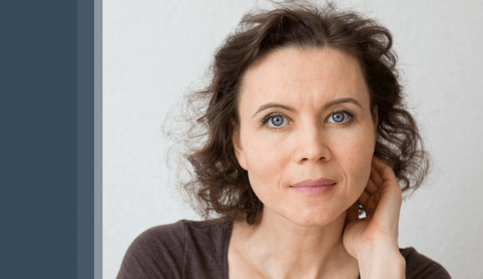 Mladá žena s tmavými vlasy zírá do kamery